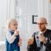 A joyful moment between a father and daughter blowing bubbles indoors, highlighting family fun.
