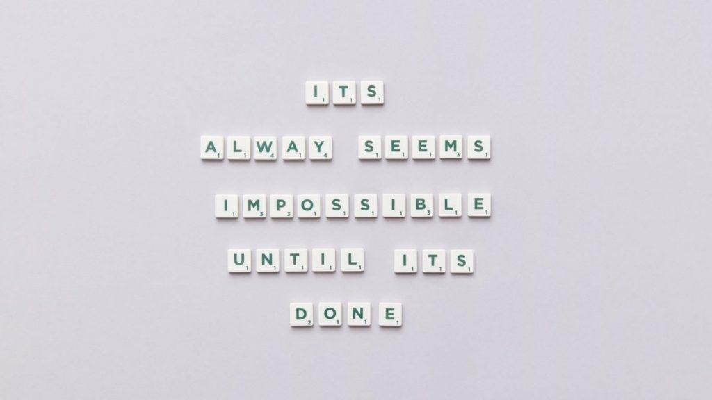 Motivational quote 'It always seems impossible until it's done' in Scrabble tiles.