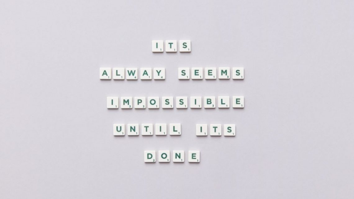 Motivational quote 'It always seems impossible until it's done' in Scrabble tiles.